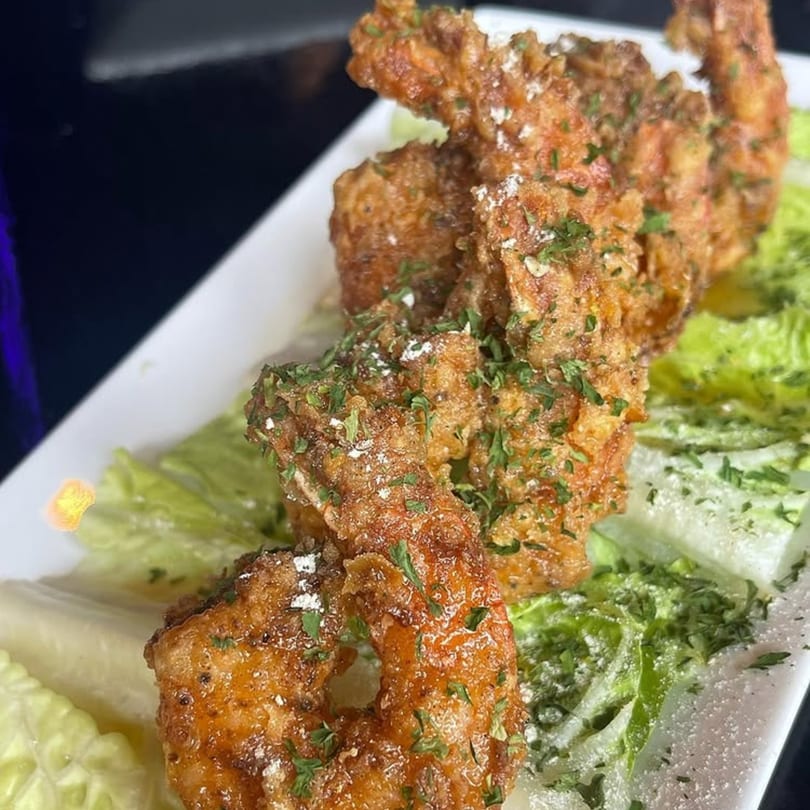 Crispy fried shrimp, garnished with parsley and powdered sugar, served on a bed of fresh lettuce.