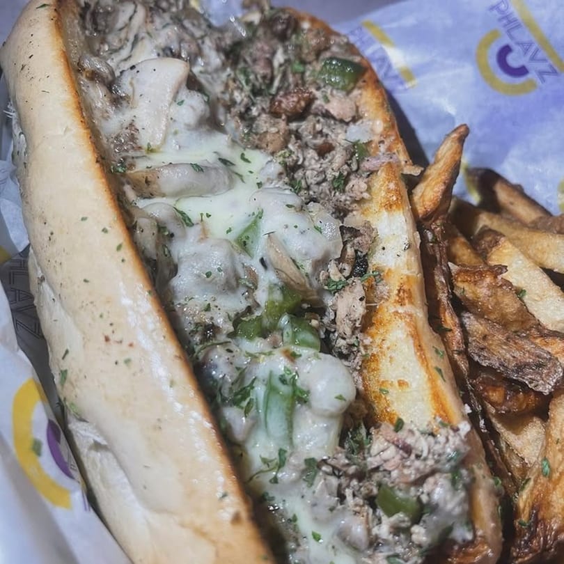 A Caribbean cheesesteak with melted cheese, green peppers, mushrooms, and fries from Phlavz.